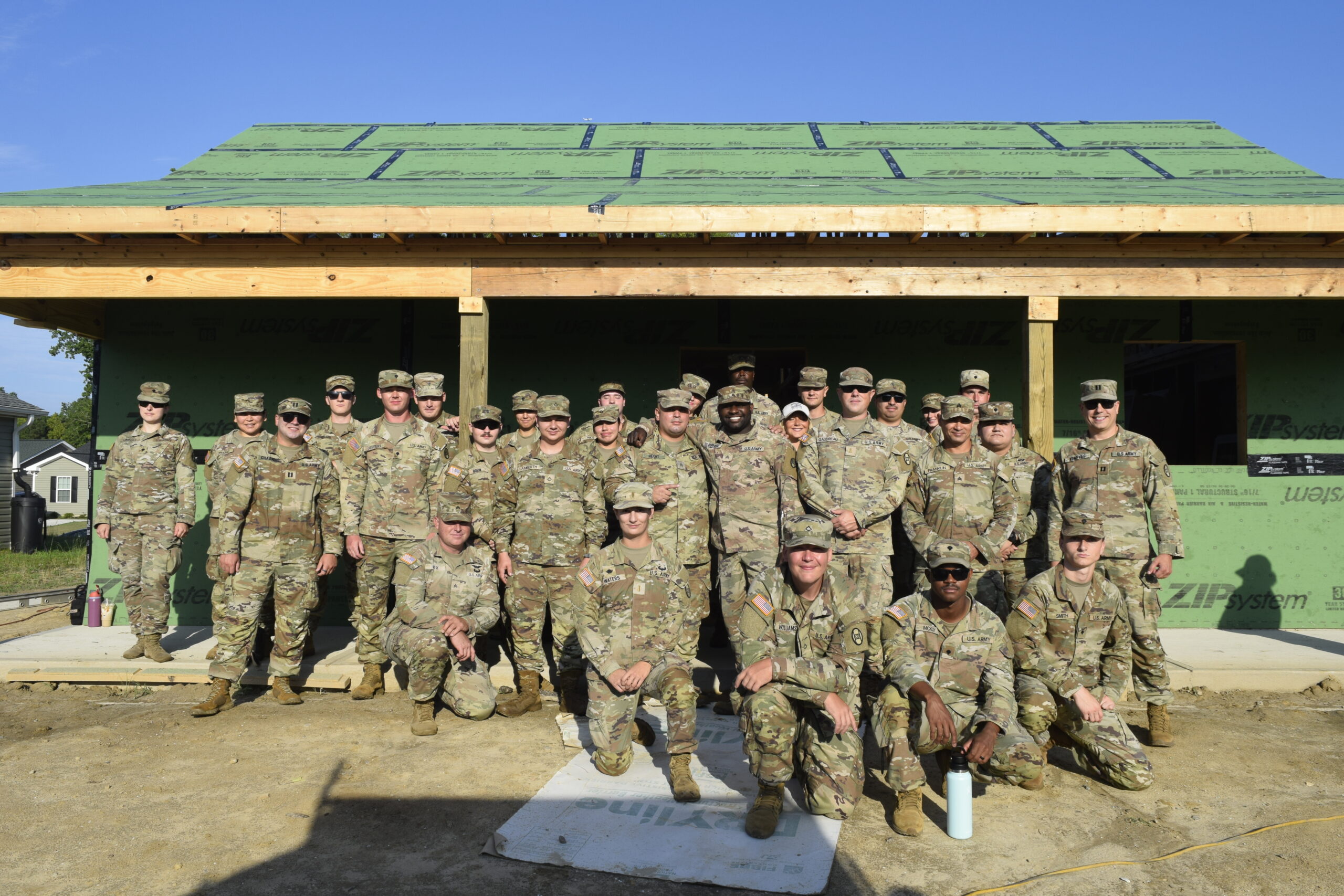 A group of Army National Guard members stand in front of a house to volunteer